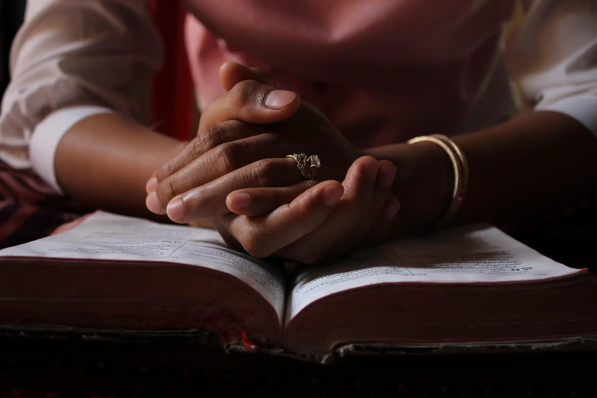 man praying while holding a bible